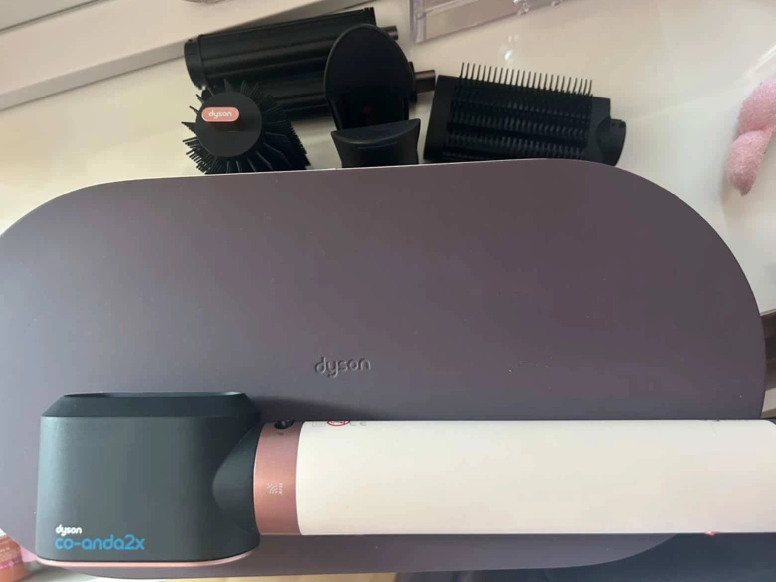 Dyson Airwrap multi-styler u bijelo-bakrenoj boji s nastavcima za oblikovanje kose.